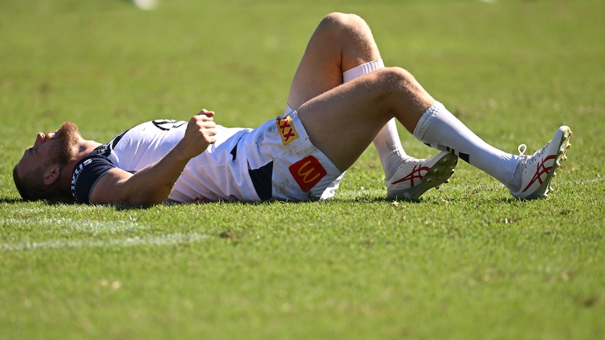 North Queensland Cowboys player Coen Hess lies on the grass during an NRL preseason game.