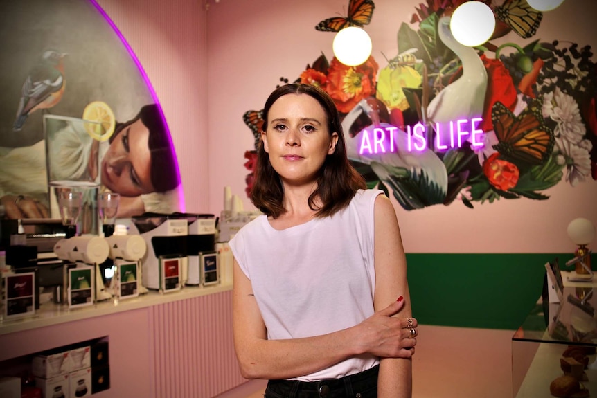 Artist Lisa King in front of a wall of art she has created.