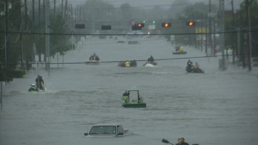 Vehicles float across a flooded road in Houston, Texas, while their passengers cling on for safety.