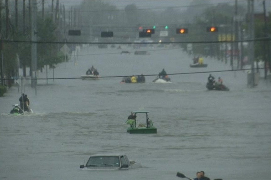 Vehicles float across a flooded road in Houston, Texas, while their passengers cling on for safety.