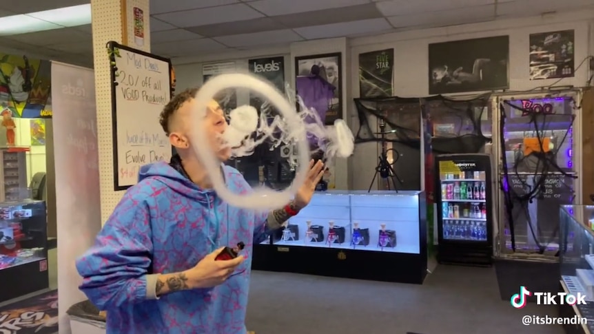 A person blows smoke rings using a vaping device.