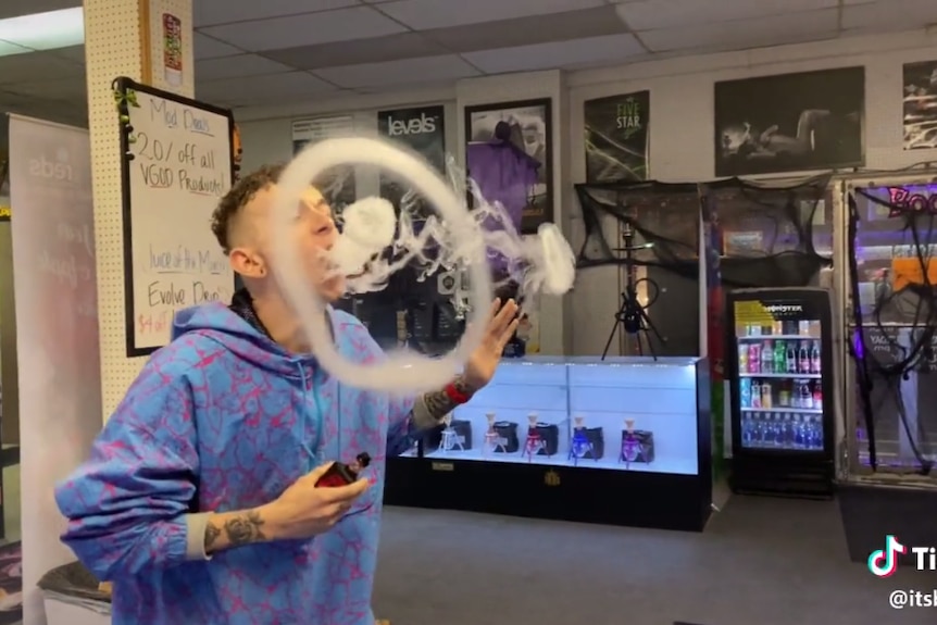 A person blows smoke rings using a vaping device.