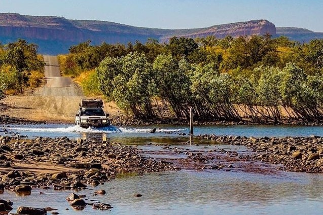 A four wheel drive vehicle crosses a river.