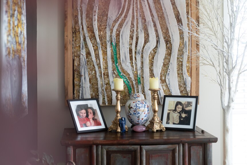 two framed picture of a young girl on a side table inside a house with candles next to frames