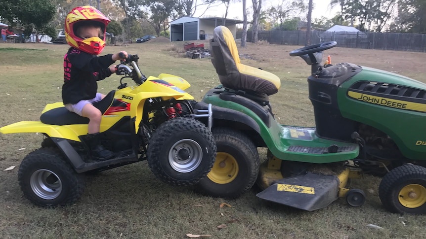 A young girl rides her small quad bike onto a ride-on mower by accident.