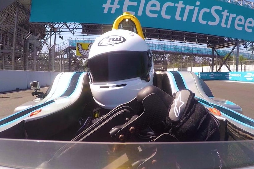 A driver at the wheel of an electrically powered Formula E racing car.