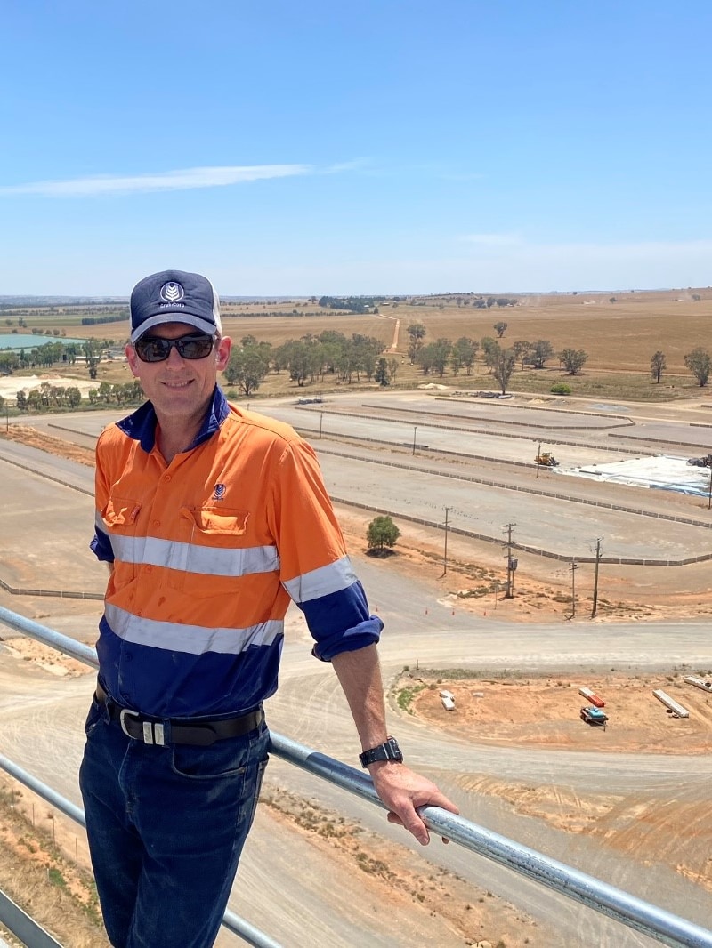 A man stands on a ledge above a grain terminal.