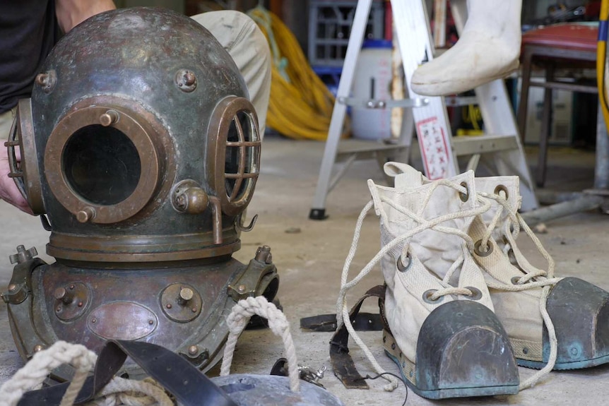 brass diving helmet and weight son left and canvas diving boots on the right