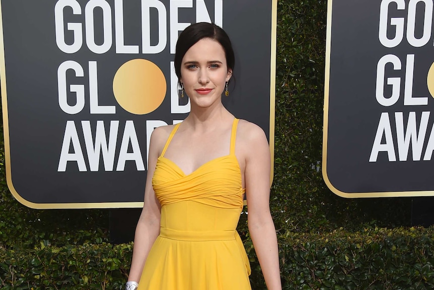 Rachel Brosnahan wears a yellow gown on the red carpet.