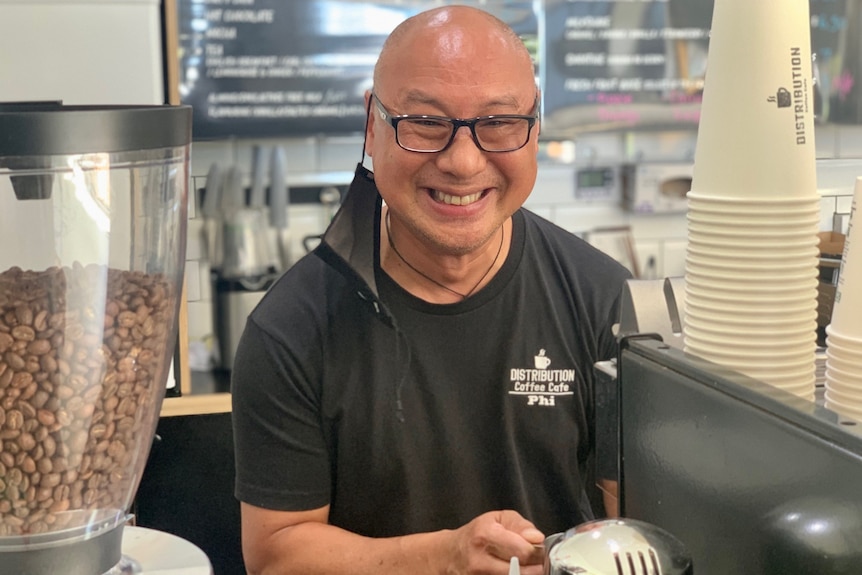 Phi Vo making coffee in a cafe smiling 