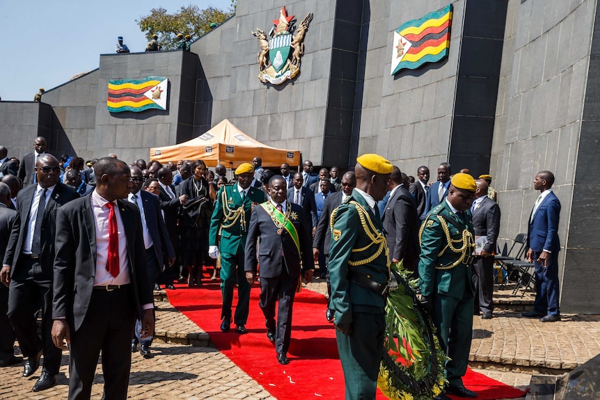 Zimbabwe President Emmerson Mnangagwa walks towards a soldier holding a wreath.