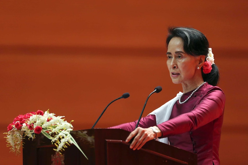 Myanmar's State Counsellor Aung San Suu Kyi during the speech. She is standing at a podium with flowers on it.