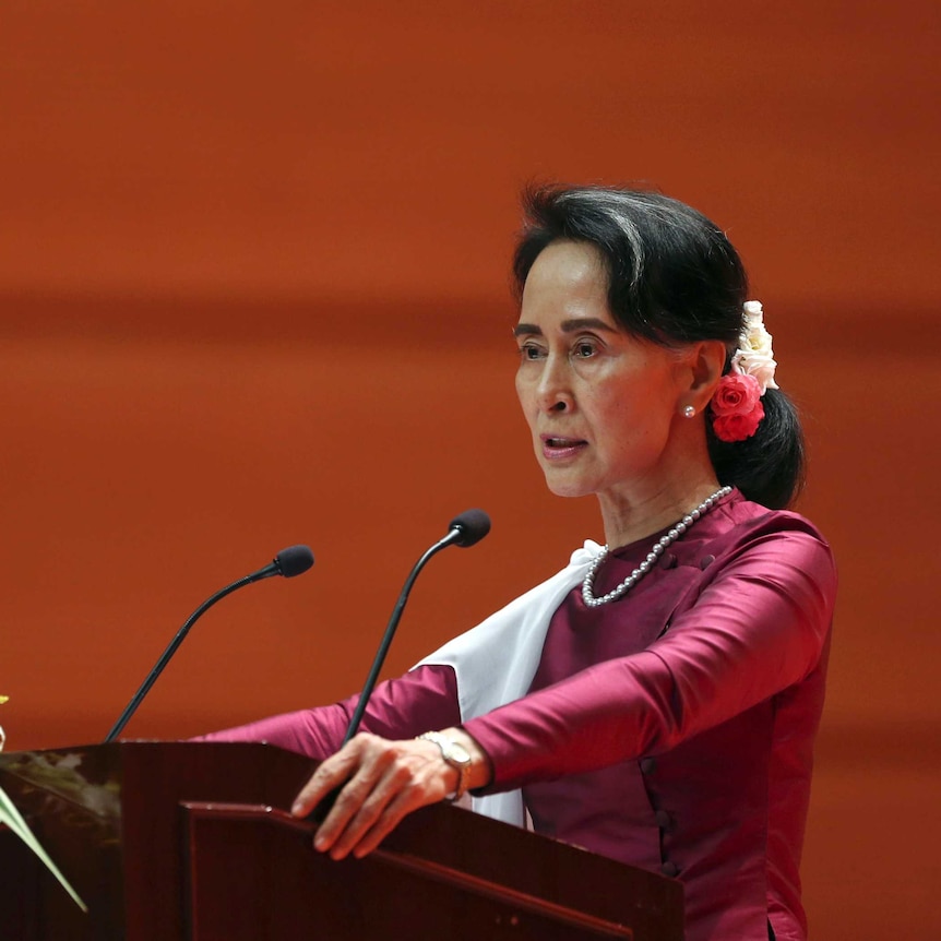 Myanmar's State Counsellor Aung San Suu Kyi during the speech. She is standing at a podium with flowers on it.