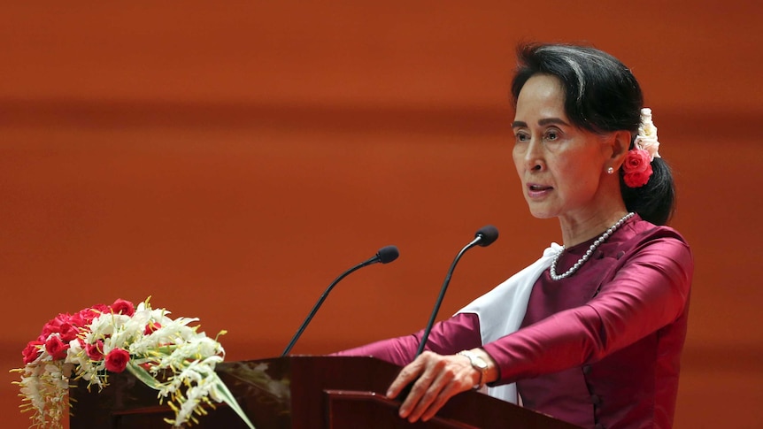 Myanmar's State Counsellor Aung San Suu Kyi during the speech. She is standing at a podium with flowers on it.