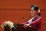Myanmar's State Counsellor Aung San Suu Kyi during the speech. She is standing at a podium with flowers on it.