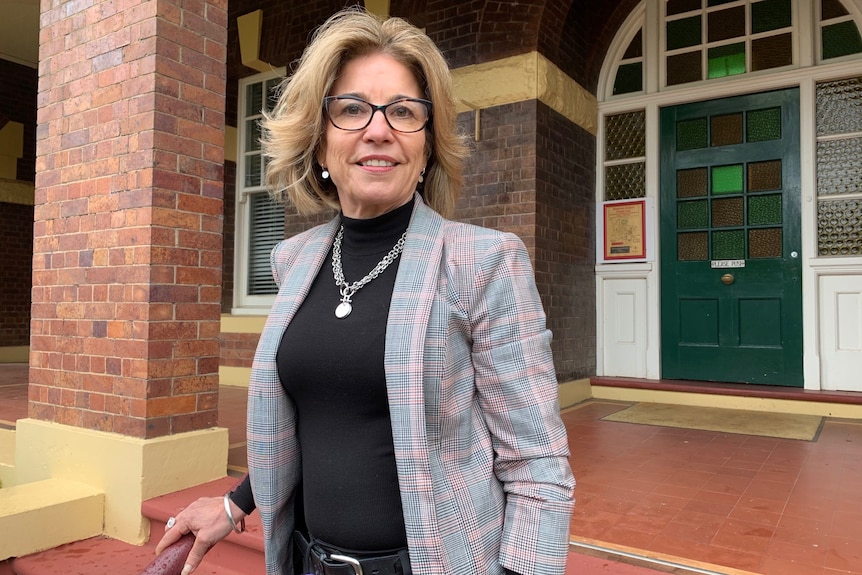 A woman with glasses is standing on some steps