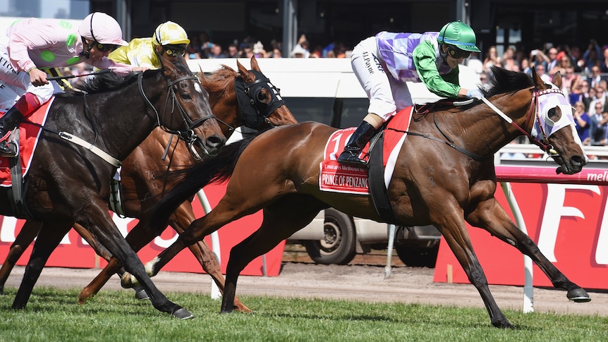 A jockey wearing pink and green silks rides a horse to finish second in the Melbourne Cup.