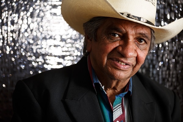 Head and shoulders image of an older Indigenous man in a suit and cowboy hat.