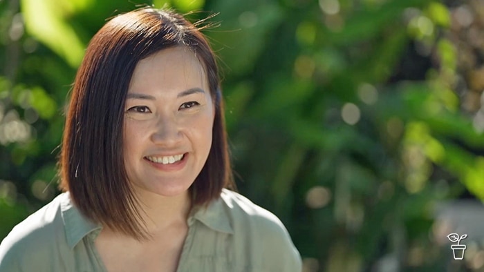 Woman smiling, sitting outdoors in the garden.