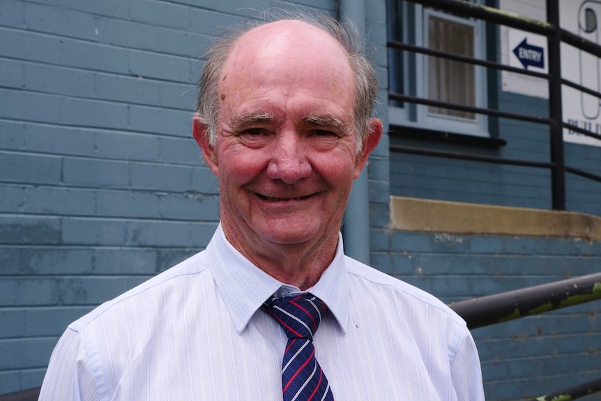 A middle-aged man smiles at the camera in collar and tie