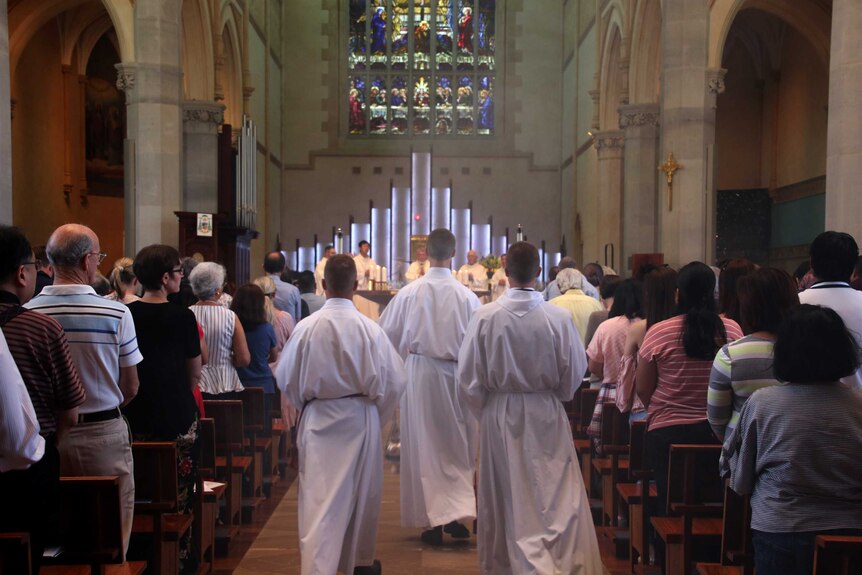 Servers walk towards the altar past parishioners lining pews at St Mary's Cathedral in Perth.