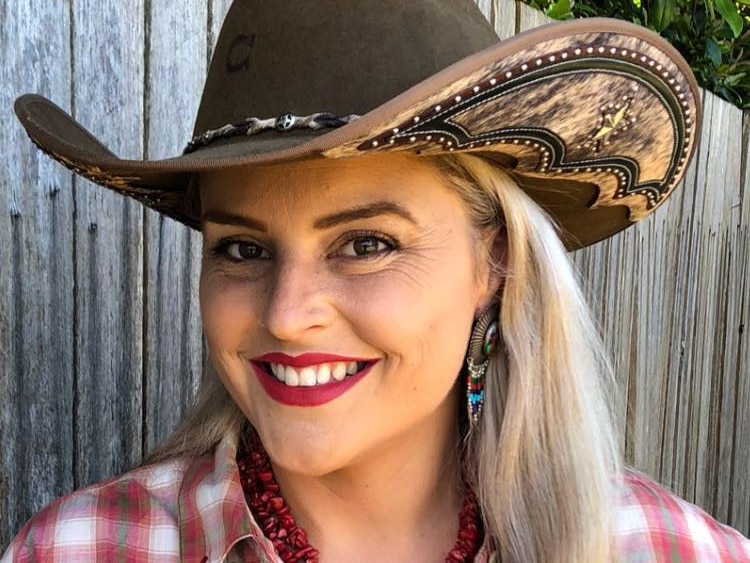 Lana Jones, wearing red checkered top and cowgirl hat smiling. 