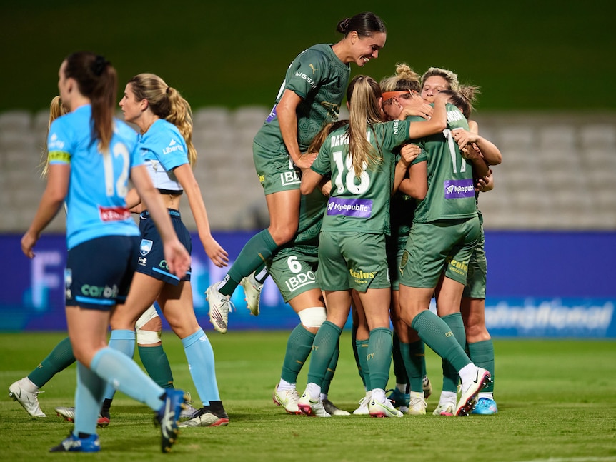 Soccer players wearing green celebrate after scoring a goal