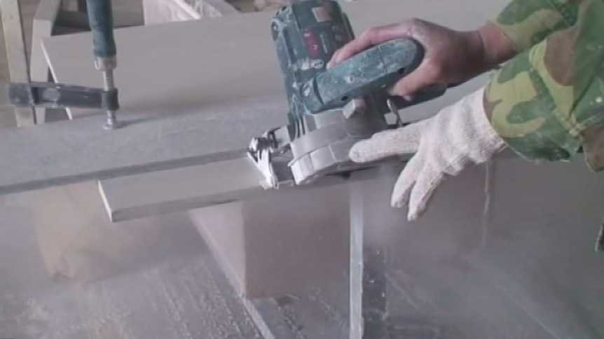 A worker cuts a slab of stone