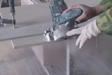 A worker cuts a slab of stone