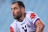 A Melbourne Storm NRL player prepares to pass the ball as South Sydney opponents approach in defence.
