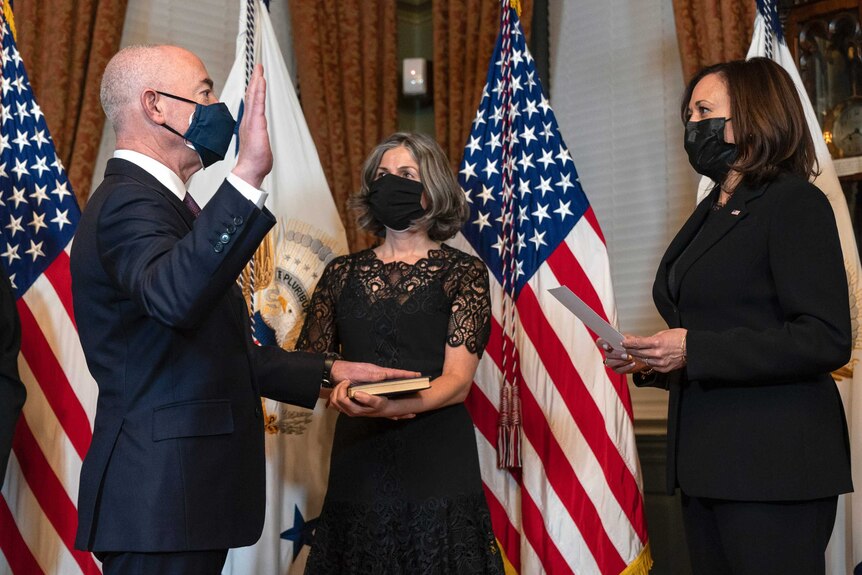 US Vice President Kamala Harris ceremonially swears in Alejandro Mayorkas as he has hand on a bible and one hand raised