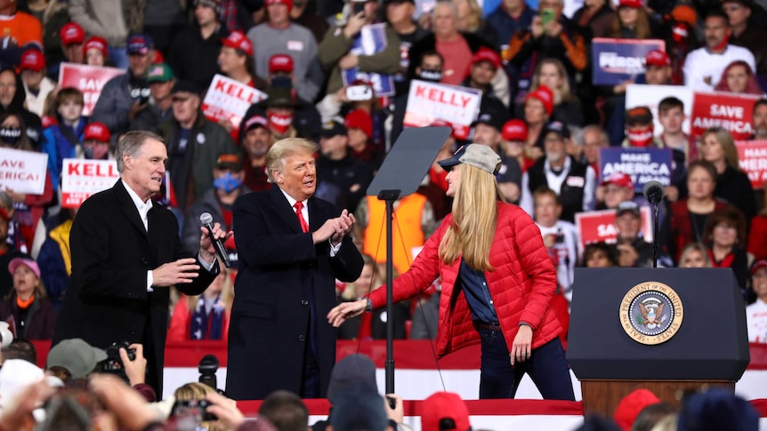 US President Donald Trump applauds as he hosts a campaign event