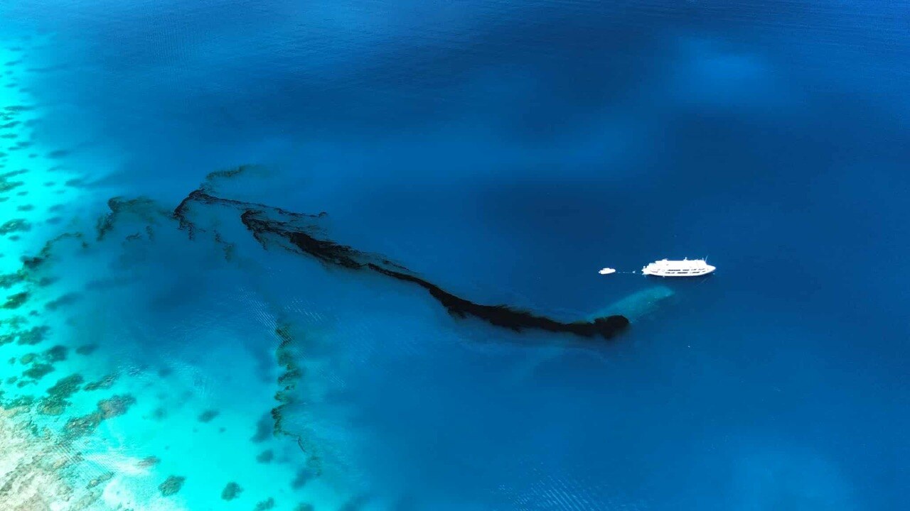 An oil leak from the Japanese World War 2 shipwreck turns the water black as a nearby boast watches on.