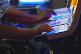 Hands playing gaming machines at Crown casino.