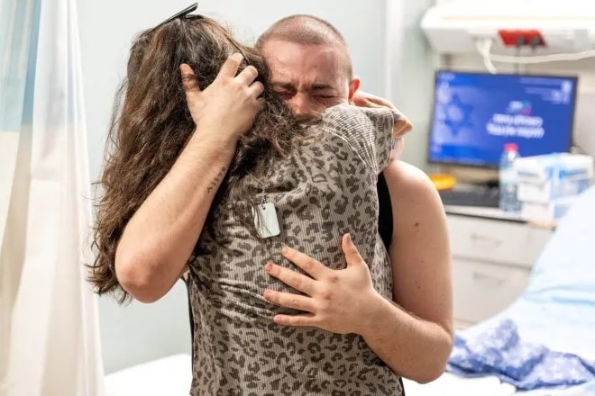 A man and a woman embrace in a hospital room.