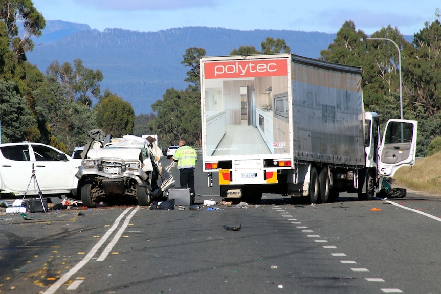A truck and cars and a crash scene as police stand amidst them.