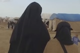 Women in burkas walk through al-Hawl, the sprawling refugee camp in Syria's Kurdish north-east.