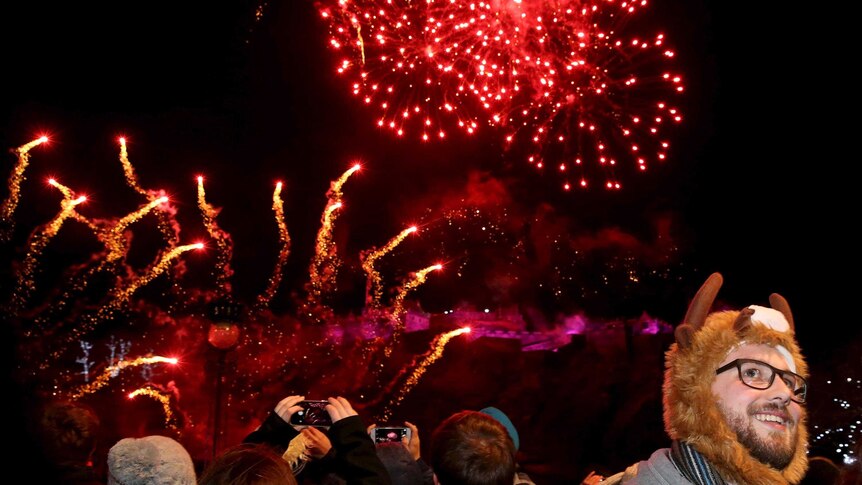 A man wearing a woollen hat watches fireworks during Hogmanay celebrations in Edinburgh.