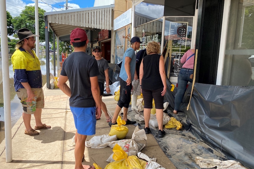 Volunteers standing out the front of a flood-damaged business.