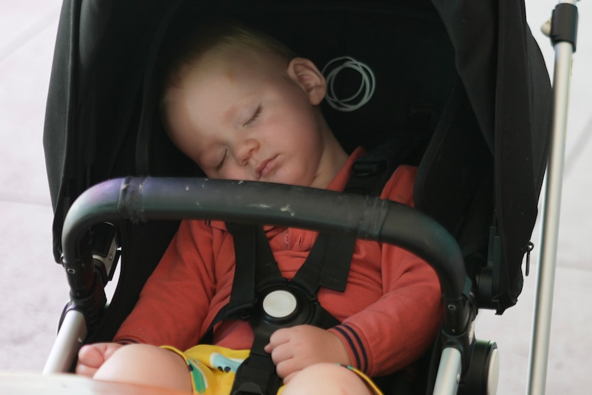 A baby boy asleep in a pram. 