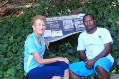 A woman and man sit together on a concrete seat at the Kokoda Trail in Papua New Guinea