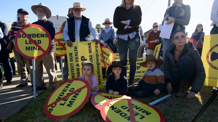 A group of people sitting and standing, holding placards 