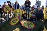A group of people sitting and standing, holding placards 