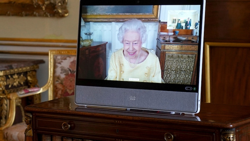 Photo shows the Queen on a tablet smiling on camera 