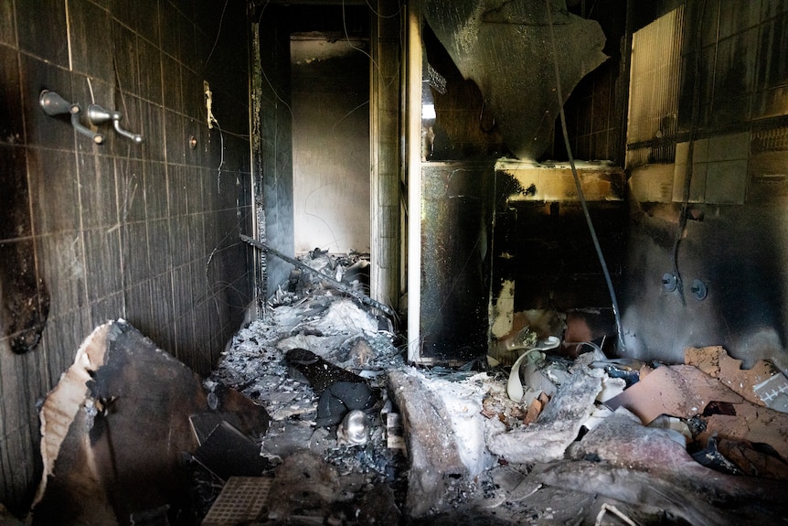 Charred rubble lies scattered across a room inside a house destroyed in a bushfire.