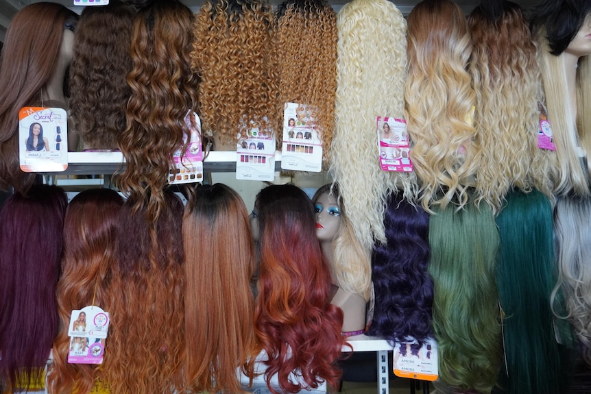 Wigs hanging from a rack.