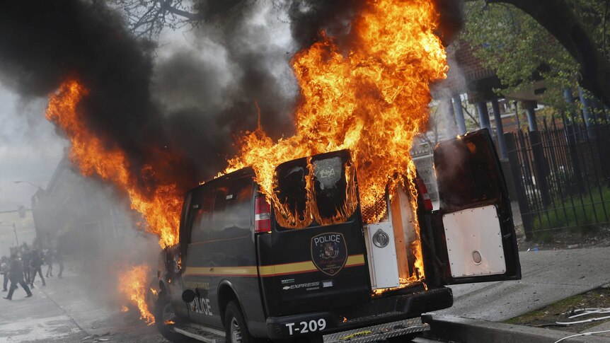 A Baltimore Metropolitan Police transport vehicle burns during clashes in Baltimore