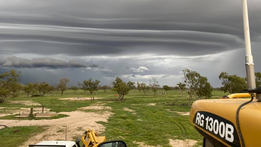 The photo has been taken by someone in a tractor with dramatic storm clouds overhead.