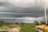 The photo has been taken by someone in a tractor with dramatic storm clouds overhead.