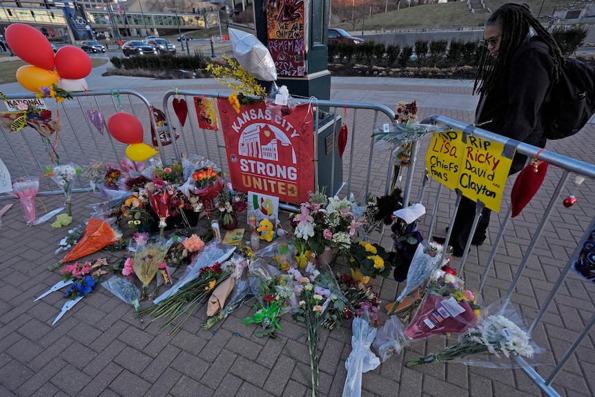 Flower tributes on the ground near a light post.